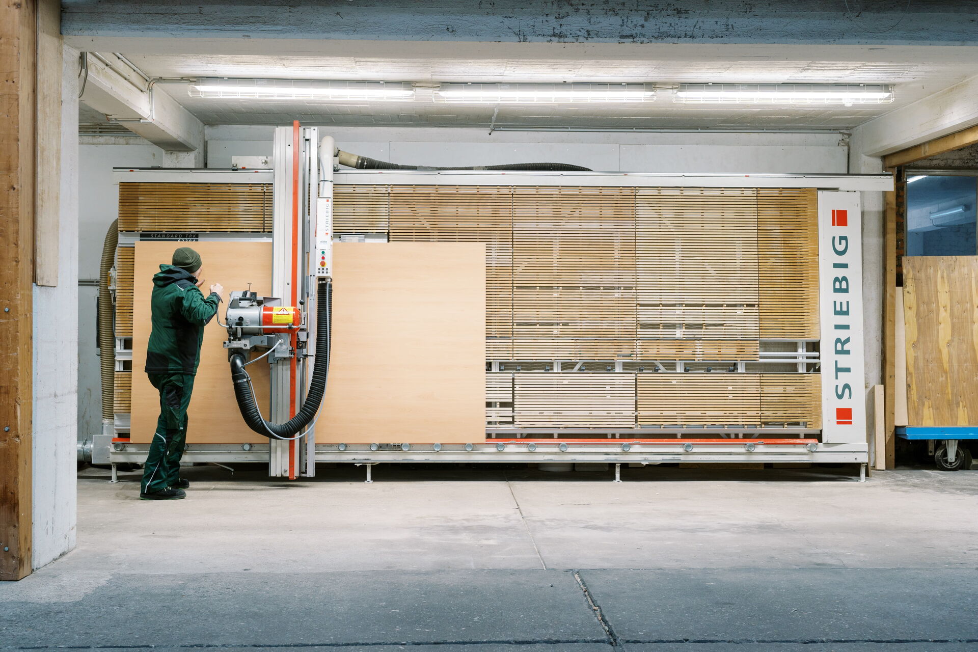 Ein Arbeiter bei Sperrholz Wölbert in Dortmund bedient eine Maschine zum Bearbeiten von Platten und Türen.