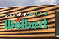 Das Logo von Sperrholz Wölbert in Dortmund präsentiert hochwertige Platten und Zubehör für Türen und Böden.