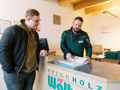 Zwei Männer beraten sich bei Sperrholz Wölbert in Dortmund über Massivholz und Dekore für Türen und Böden.